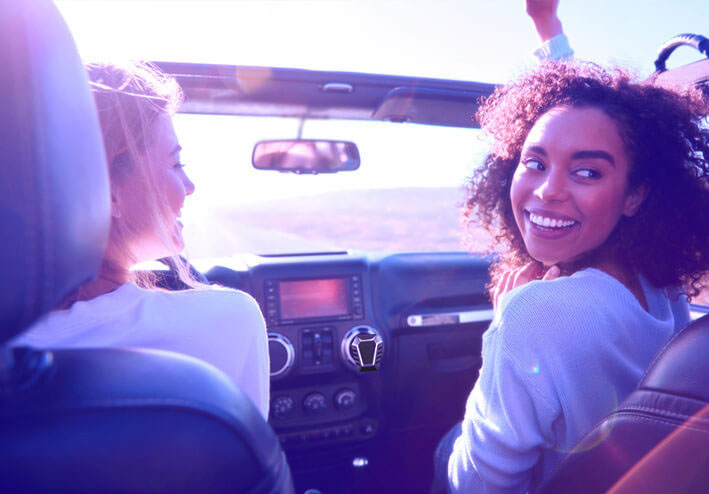 Mulheres sorrindo andando em carro no por do sol